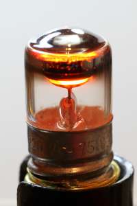 Picture of a glowing lamp after several years of service: it still glows but the glass is blackened by the metal sputtered off the electrodes. (click to enlarge)
