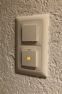 This illuminated switch contains a small neon glow lamp (and ballast resistor) in parallel with it. It only glows when the light is off. (click to enlarge)